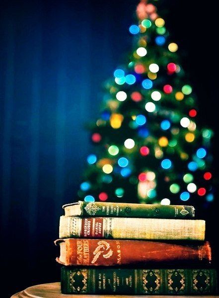 Stack of books with Christmas tree in background